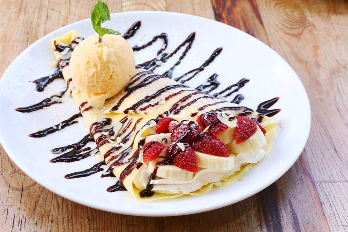 Closeup of vanilla ice cream with crepes and strawberry served at Crepe Station.