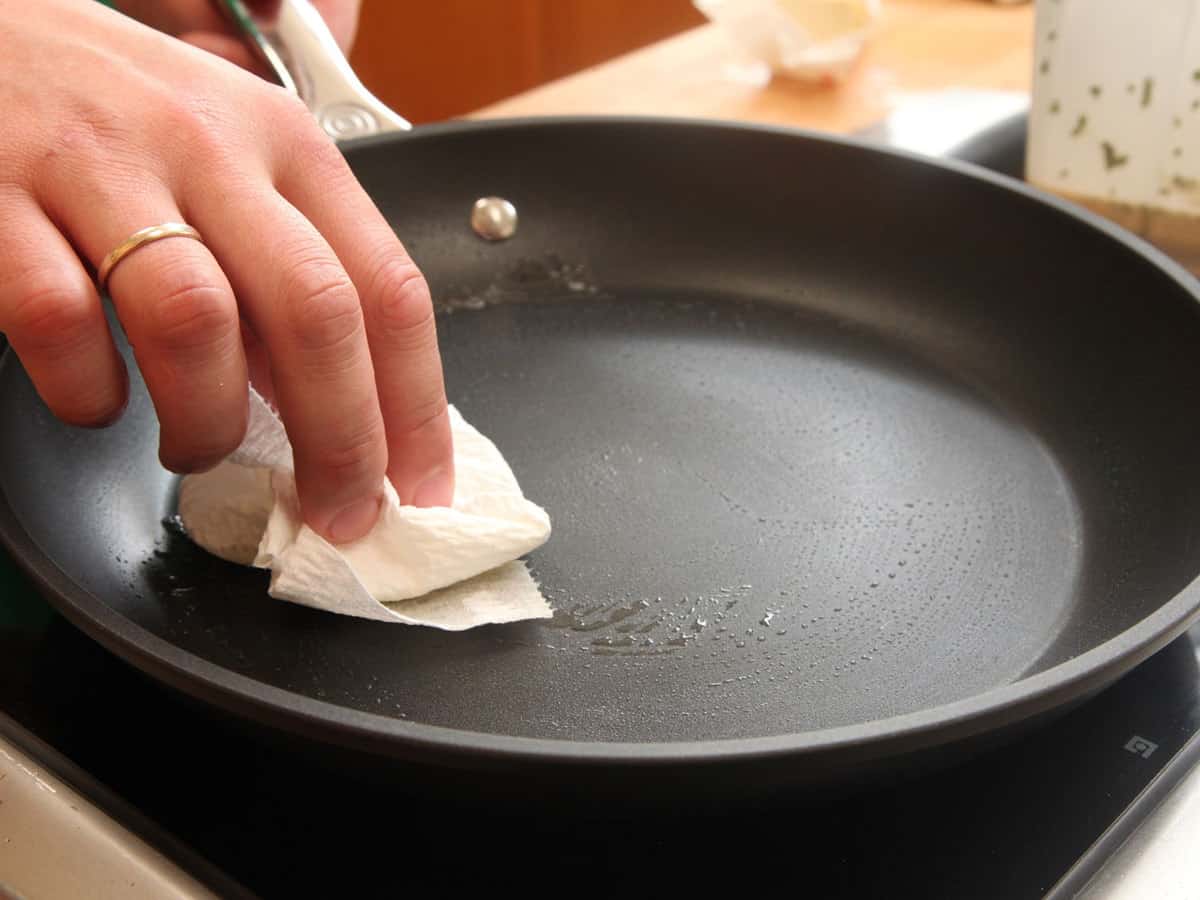 Rubbing butter into the interior of a nonstick skillet, using a paper towel